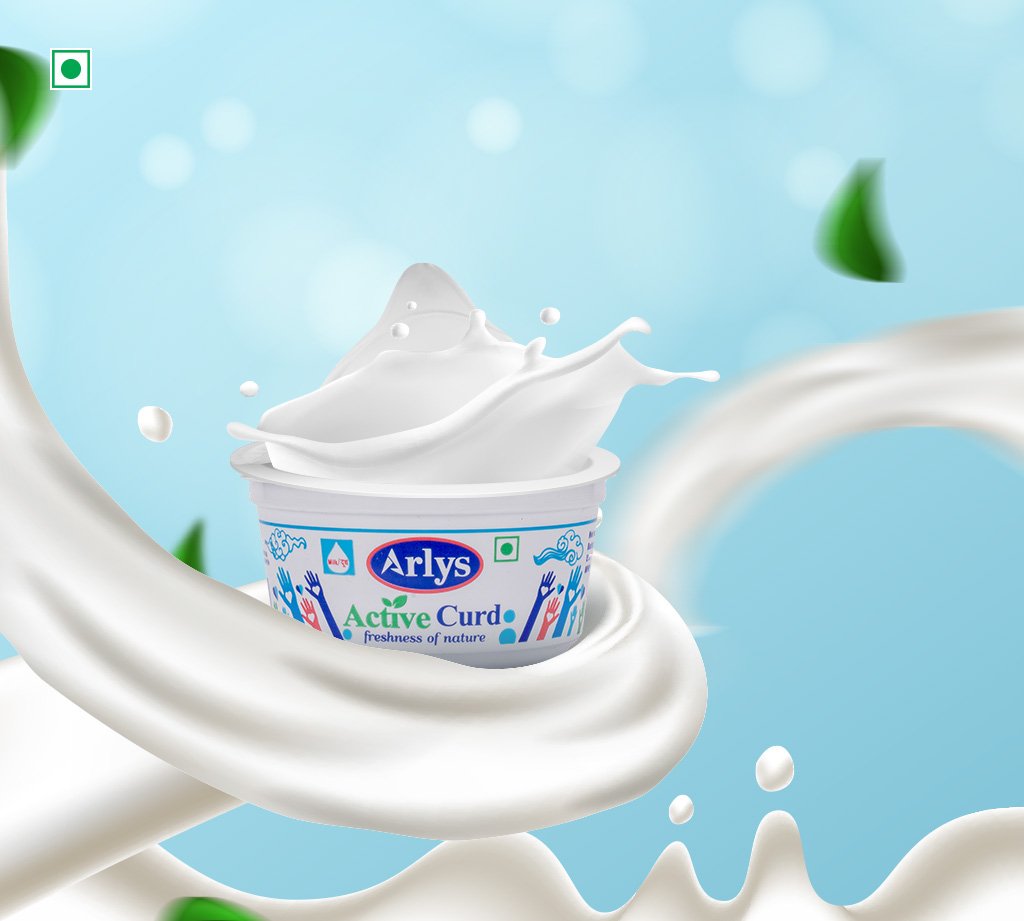 Container of Arlys Active Curd yogurt with a dramatic splash of milk swirling around it against a blue sky background.