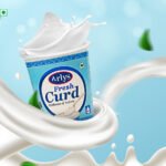 Arlys Fresh Curd yogurt cup with milk splash and swirling stream against a blue backdrop.