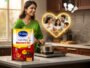 Woman in a green saree holding Arvind Kachi Ghani Mustard Oil box in a kitchen, cooking on a pot on the stove; a glowing heart frame shows a happy family dinner in the background.