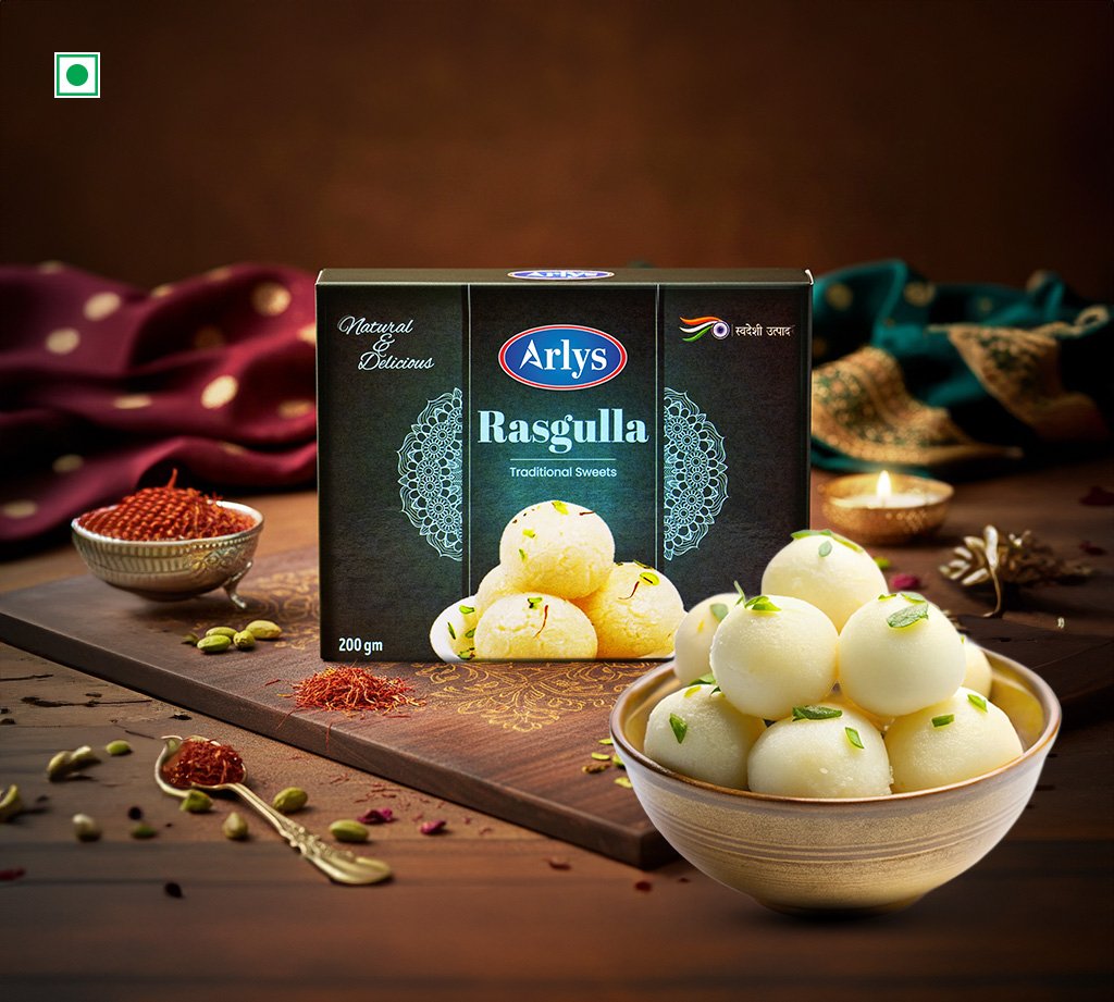 Box of Arlys Rasgulla traditional sweets with a bowl of white rasgulla in foreground and spice decor in the background
