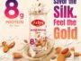 Arlys Kesar Badam Shake bottle at center with almonds and splash, promoting 8g protein per pack and gold theme chocolates and cream background
