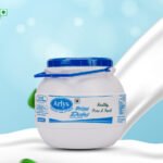 White yogurt container with a blue lid labeled Arlys Prime Dahi on a blue-and-white abstract background.