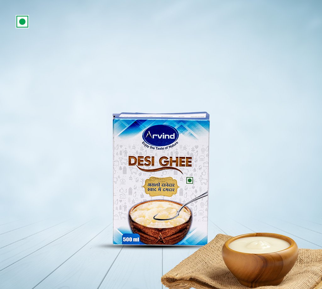Arvind Desi Ghee carton (500 ml) with a wooden bowl of ghee and spoon in front on a pale blue background.