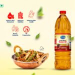 Bottle of Arvind Kachi Ghani Mustard Oil beside a copper pan of mixed vegetables with health-benefit icons above the dish (low cholesterol, nutrition, skin health, immunity, no preservatives).