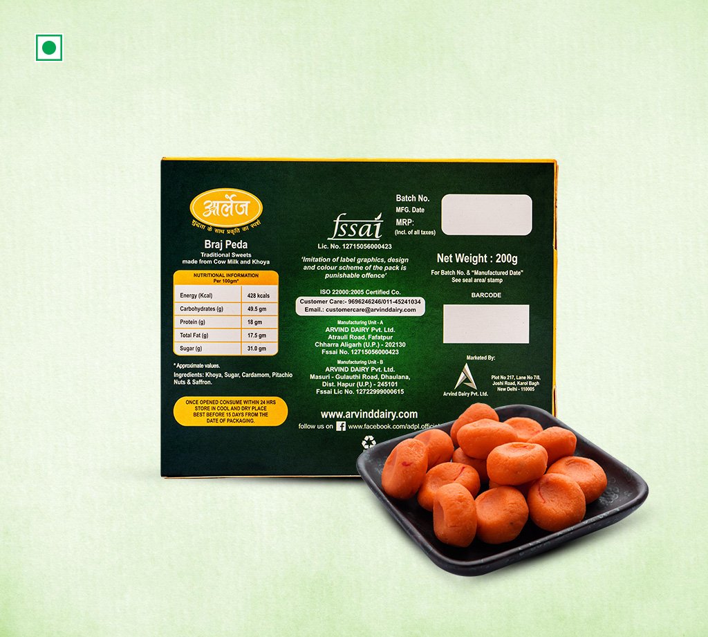 Green Braj Peda sweet box with a black plate of orange pedas in front on a light green background.