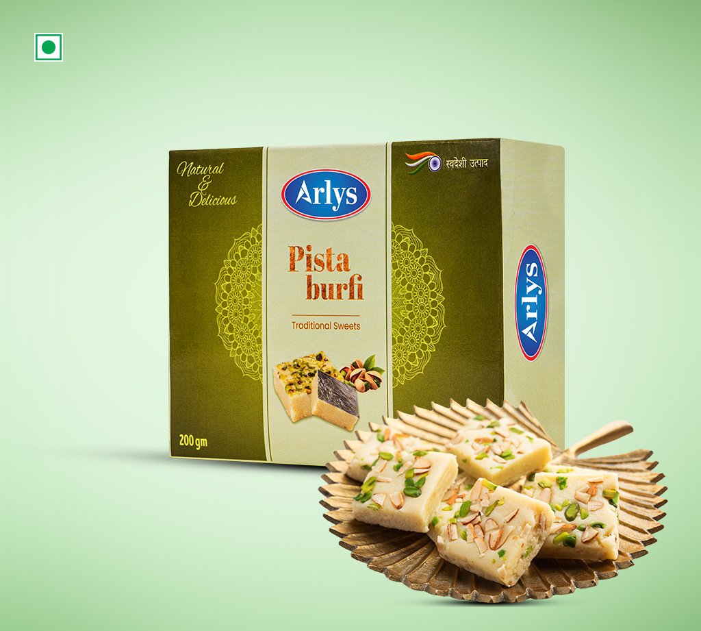 Arlys Pista Burfi box with pistachio‑topped burfi pieces on a decorative plate.