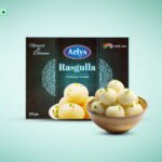 Box of Arlys Rasgulla traditional sweets with a bowl of white rasgulla in front on a light teal background
