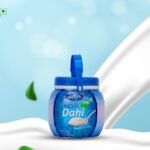 Blue-lidded jar of Fresh Dahi yogurt on a white curved surface with a pale blue background.
