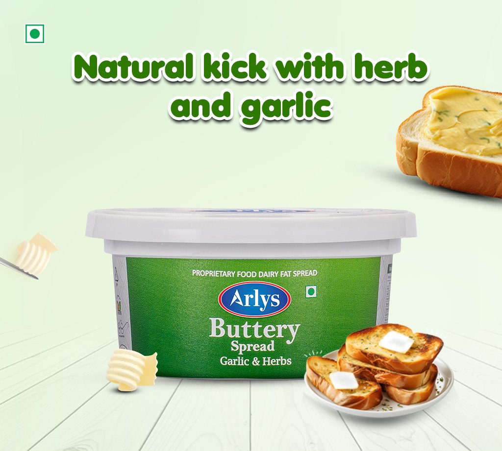 Tub of Arlys Garlic & Herbs Butter Spread on a pale green background with bread slices and butter curls nearby.