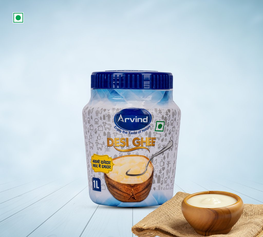 Jar of Arvind Desi Ghee with blue lid (1 L) on a light blue background, with a bowl of ghee nearby and a spoon dipped in it.