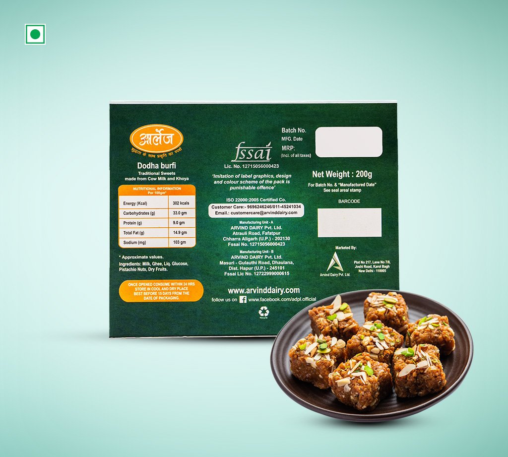 Green box of Dodha burfi traditional sweets with a plate of square, nut-topped burfi on a teal background.