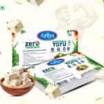 Arlys Vegetable Tofu packaging with cubes of tofu, a bowl of tofu cubes, and leafy greens on a light background, highlighting zero cholesterol claim.